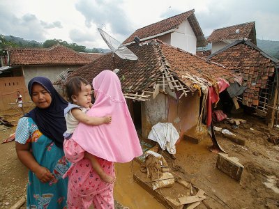 des villageois devant des maisons détruites par les inondations à Banjar Irigasi, dans la province de Banten, en Indonésie, le 2 janvier 2020 - SAMMY [AFP]