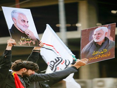 Un Irakien tient les portraits du puissant général Qassem Soleimani et d'un chef de la milice irakienne Hachd al-Chaabi, tués par une frappe américaine, pendant leurs obsèques à Bagdad, le 4 janvier 2020 - SABAH ARAR [AFP]