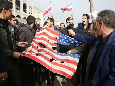 Des Iraniens déchirent un drapeau américain, le 3 janvier 2020 à Téhéran - ATTA KENARE [AFP]