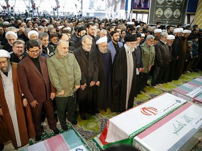 le Guide suprême iranien, l'ayatollah Ali Khamenei (à l'avant), prie devant les cercueils du général Qassem Soleimani et du chef paramilitaire irakien Abou Mehdi al-Mouhandis à l'Université de Téhéran le  6 janvier 2020 - - [IRANIAN SUPREME LEADER'S WEBSITE/AFP]