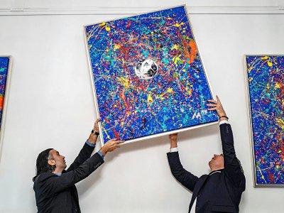Kerem Akar (g), le père de Mikail Akar, et le marchand d'art Marcus Schaefer accrochent un tableau du jeune prodige dans une galerie de Berlin, le 13 décembre 2019 - John MACDOUGALL [AFP/Archives]