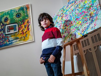 L'artiste allemand de 7 ans Mikail Akar pose devant ses peintures "Champi" (d) et "Homme tournesol" avant l'ouverture de son exposition "Manus 11" à Berlin, le 13 décembre 2019 - John MACDOUGALL [AFP/Archives]