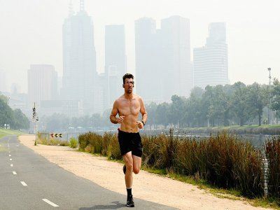 Un homme fait son jogging dans une atmosphère enfumée, à Melbourne, le 14 janvier 2020 - William WEST [AFP/Archives]