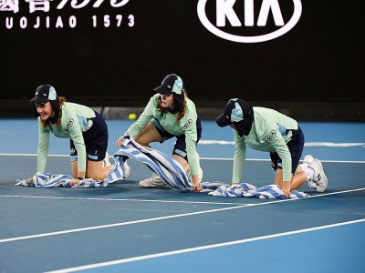 Des ramasseuses de balles épongent un court lors de l'Open d'Australie, le 20 janvier 2020 à Melbourne - Manan VATSYAYANA [AFP]