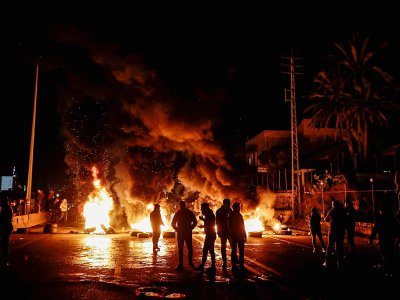 Des manifestants libanais devant des pneus enflammés, sur une route allant de Beyrouth à Byblos, le 21 janvier 2020 - JOSEPH EID [AFP]