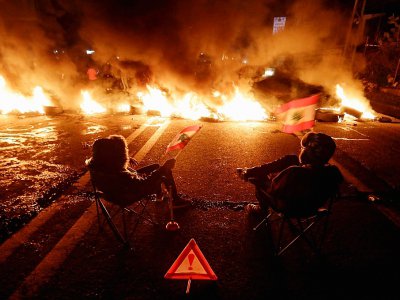 Des manifestants libanais devant des pneus enflammés, sur une route allant de Beyrouth à Byblos, le 21 janvier 2020 - JOSEPH EID [AFP]