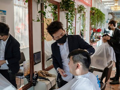 Des coiffeurs portent un masque de protection dans un salon de Pékin le 23 janvier 2020 - NICOLAS ASFOURI [AFP]