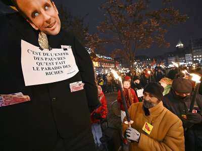 A Strasbourg, un manifestant brandissait un pantin en costume noir avec un masque d'Emmanuel Macron et des faux billets sortant des poches, le 23 janvier 2020 - FREDERICK FLORIN [AFP]