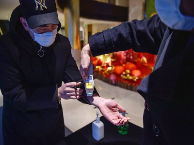 L'employé d'un hôtel de Wuhan contrôle la température d'un nouvel arrivant, le 24 janvier 2020 - Hector RETAMAL [AFP]