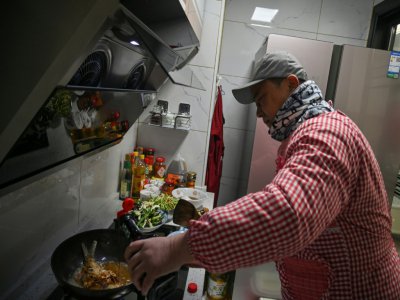 Pen Lixing prépare le 24 janvier 2020 le repas du réveillon du Nouvel an chinois à Wuhan, ville coupée du reste du monde en raison de la propagation d'un nouveau coronavirus. - Hector RETAMAL [AFP]