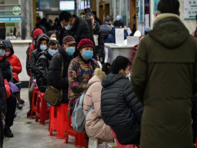Protégés par des masques, des habitants de Wuhan font la queue le 24 janvier 2020 devant un hôpital de la ville, coupée du reste du monde en raison de la propagation d'un nouveau coronavirus. - Hector RETAMAL [AFP]