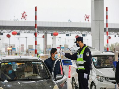 Un policier contrôle la température d'un automobiliste à un péage autoroutier, le 24 janvier 2020 à Wuhan, épicentre du nouveau coronavirus en Chine - STR [AFP]