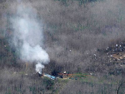 De la fumée s'échappe des débris de l'hélicoptère qui transportait Kobe Bryant, sa fille et sept autres personnes, le 26 janvier 2020 à Calabasas, près de Los Angeles - Mark RALSTON [AFP]