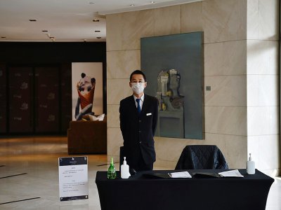 Dans un hôtel de Wuhan, un employé chargé de prendre la température de quiconque entre dans le bâtiment, le 29 janvier 2020 - HECTOR RETAMAL [AFP]