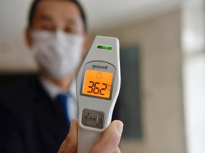 Un employé chargé de prendre la température des clients dans un hôtel de Wuhan, le 29 janvier 2020 - HECTOR RETAMAL [AFP]
