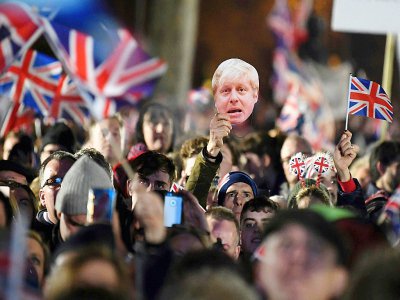 Des partisans du Brexit agitent des drapeaux britanniques et un masque du Premier ministre Boris Johnson à Londres le 31 janvier 2020 - DANIEL LEAL-OLIVAS [AFP]