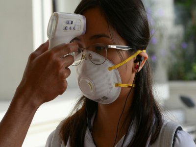 Une étudiante portant un masque de protection se fait contrôler la température avant d'entrer sur son campus, le 31 janvier 2020 à Manille, aux Philippines - Ted ALJIBE [AFP/Archives]