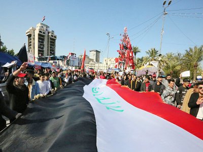 Des manifestants antigouvernementaux agitent un drapeau irakien géant sur la place Tahrir, dans le centre de la capitale Bagdad, le 2 février 2020 - SABAH ARAR [AFP]