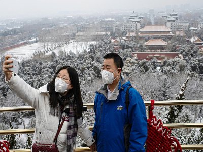 Deux personnes se prennent en photo en étant masqués, le 2 février 2020 à Pékin - NICOLAS ASFOURI [AFP]