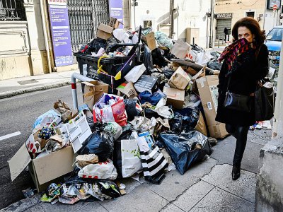 Une passante près d'un empilement d'ordures non ramassées en raison d'une grève des éboueurs, à Marseille le 3 février 2020 - GERARD JULIEN [AFP]