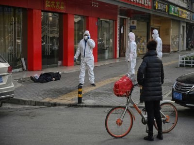 Les services de secours interviennent après le décès d'une personne (au sol) dans une rue de Wuhan, le 30 janvier 2020 - Hector RETAMAL [AFP/Archives]