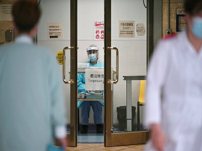 Un membre du personnel médical en combinaison de protection (c) attend de prendre la température des personnes qui arrivent à l'hôpital Princess Margaret, le 4 février 2020 à Hong Kong - Anthony WALLACE [AFP]