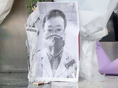 Une photo du médecin Li Wenliang, devant laquelle a été déposé un bouquet de fleurs, devant une aile de l'hôpital de Wuhan, en Chine, le 7 février 2020 - STR, STR [AFP]