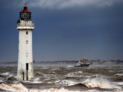 Un bateau de pêche passe le 9 février 2020 devant le phare de New Brighton, dans le nord-ouest de l'Angleterre, où la tempête Ciara est arrivée - Paul ELLIS [AFP]