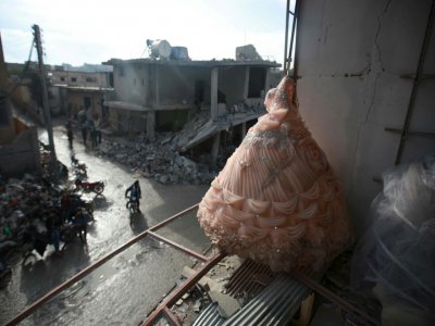 Une robe de mariée dans la vitrine détruite par un bombardement d'un magasin de la province syrienne d'Idleb, le 8 décembre 2019 - Aaref WATAD [AFP/Archives]