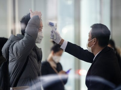 Dans un immeuble de bureaux de Shanghai, un agent de sécurité vérifie la température d'un employé.