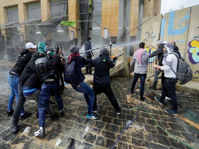 Des manifestants anti-gouvernementaaux s'en prennent à une section des blocs de ciment protégeant les institutions de l'Etat dans le centre de Beyrouth lors des manifestations du 11 février 2020 pour empêcher un vote de confiance en faveur d'un nouve - JOSEPH EID [AFP]