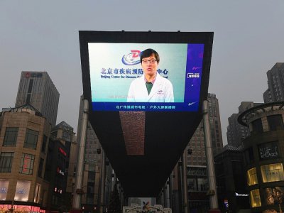Un écran géant installé dans un centre commercial de Pékin informe le 12 février 2020 des derniers développements du coronavirus - GREG BAKER [AFP]