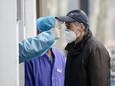 La température d'un  homme est vérifiée le 13 février à devant l'entrée d'un hôpital à Shanghai - NOEL CELIS [AFP]