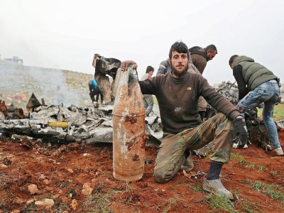Un rebelle syrien pose avec un débris d'un hélicoptère de l'armée syrienne abattu, dans la province d'Alep (Syrie), le 14 février 2020 - Omar HAJ KADOUR [AFP]