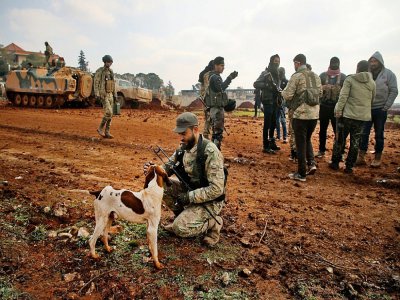 Des rebelles syriens soutenus par Ankara cajole un chien dans le village de Miznaz, dans la province d'Alep, en Syrie, le 14 février 2020 - AAREF WATAD [AFP]