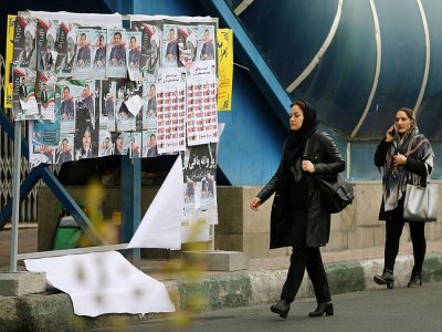 Des Iraniennes circulant dans une rue de Téhéran devant des affiches électorales le 19 février 2020 - ATTA KENARE [AFP]