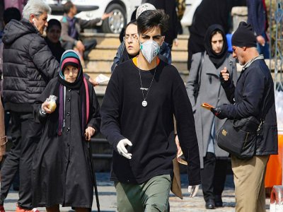 Des piétons, certains portant un masque de protection, dans une rue de Téhéran, le 22 février 2020 en Iran - ATTA KENARE [AFP]