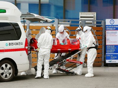 Du personnel médical en combinaison de protection transportent un malade atteint du COVID-19 dans un hôpital de Chuncheon, le 22 février 2020 en Corée du Sud - - [YONHAP/AFP]