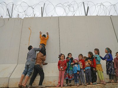 Des enfants déplacés syriens
tentent d'escalader le mur de la frontière turque, dans la province d'Idleb, le 21 février 2020 - AAREF WATAD [AFP]