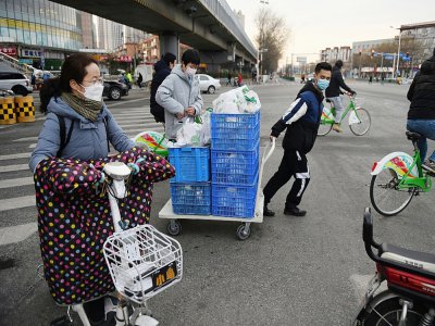 Des empployés d'un restaurant transportent sur un chariot des cageots de légumes à livrer à domicile, le 18 février 2020 à Tongzhou, dans l'est de Pékin - GREG BAKER [AFP]