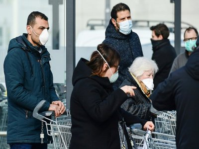 Des personnes portant des masques de protection vont faire leurs courses dans un supermarché, le 23 février 2020 à Caslpusterlengo, en Italie - Miguel MEDINA [AFP]