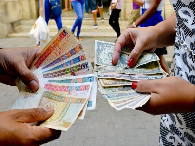 Des billets cubains (CUC) (g) et des dollars dans une rue de La Havane, le 10 décembre 2019 - YAMIL LAGE [AFP]