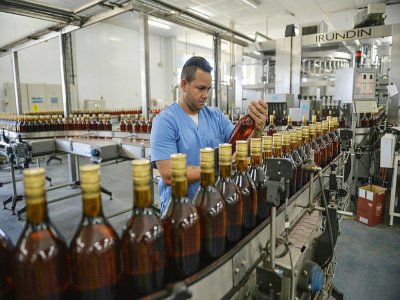 Un employé vérifie les bouteilles de rhum Havana Club sur une chaîne de production, le 15 mars 2018 dans la distillerie de l'entreprise à San José de Las Lajas, à Cuba - YAMIL LAGE [AFP/Archives]