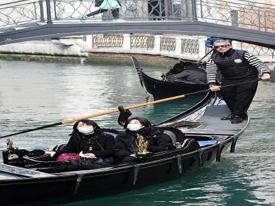 Des tpiristes asiatiques portent des masques de protection lors d'un tour en gondole à Venise, le 24 février 2020. - ANDREA PATTARO [AFP]