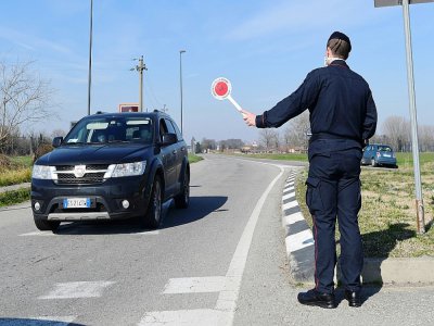 Un policier italien stoppe une voiture à un point de contrôle près de la petite ville de Castiglione d'Adda, au sud-est de Milan, le 24 février 2020. - Miguel MEDINA [AFP]
