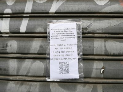 Une affiche annonce la fermeture d'un magasin en raison de l'épidémie de nouveau coronavirus en Italie, le 25 février 2020 dans le quartier chinois de Milan - Miguel MEDINA [AFP]
