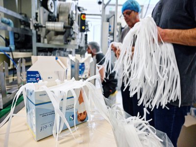 Des employés emballent des masques de protection resppiratoire sur une ligne d'assemblage de l'usine Valmy, le 28 février 2020 à Mably, dans la Loire - PHILIPPE DESMAZES [AFP]
