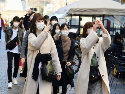 Des touristes portent des masques de protection contre le Covid-19 dans les rues de Milan, le 28 février 2020 - Miguel MEDINA [AFP]