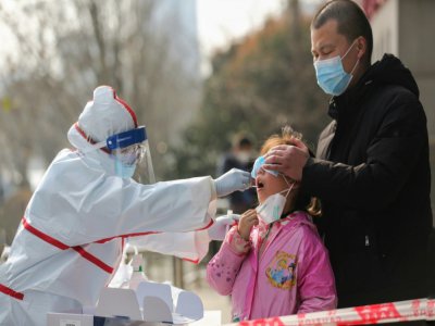 Un membre du personnel médical prélève un échantillon buccal chez une jeune habitante de Wuhan, le 5 mars 2020 - STR [AFP]