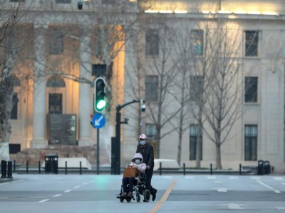 Une personne dans une chaise roulante et son accompagnateur dans les rues de Wuhan, le 4 mars 2020 - STR [AFP]